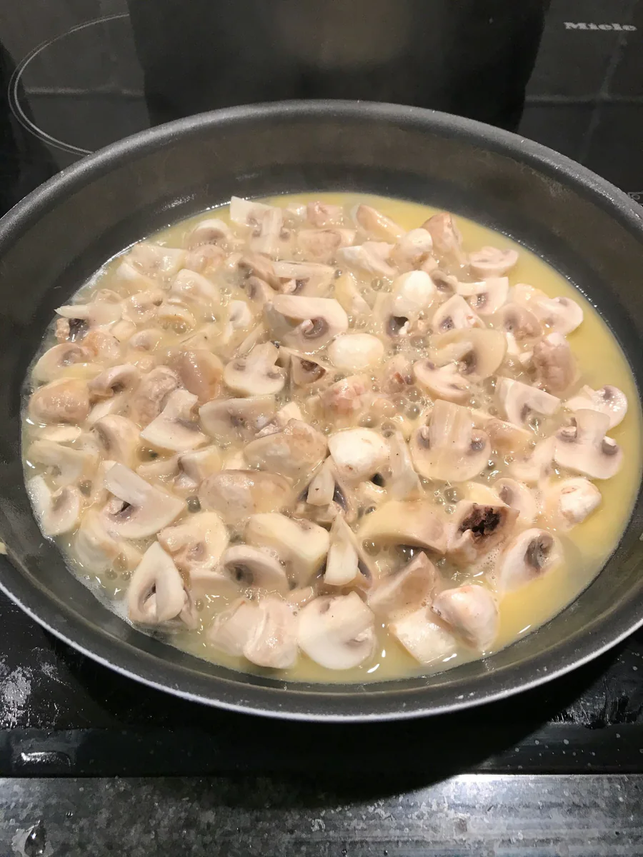 Geschnittene Champignons in einer Pfanne garen.