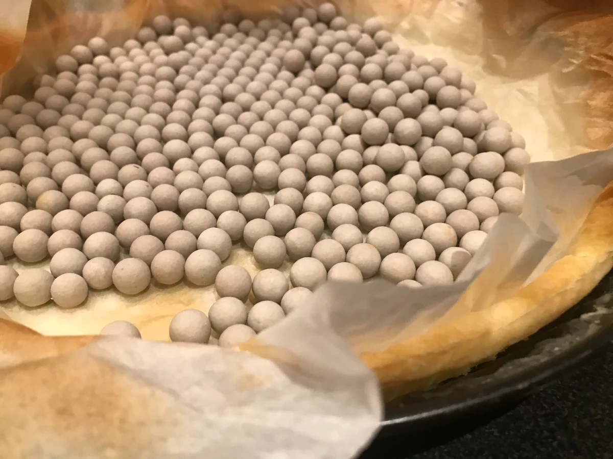 Tart case lined with baking paper and baking beans for blind baking.
