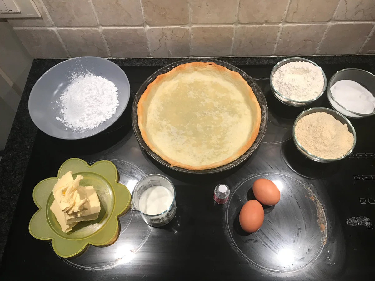Ingredients and pastry case for a frangipane tart on the worktop.