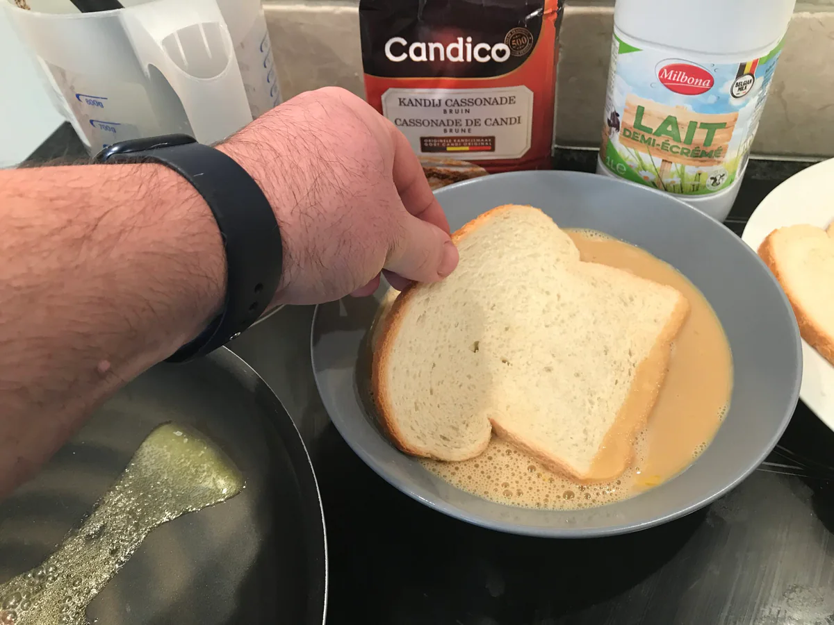 Dipping a slice of bread in the egg mixture.