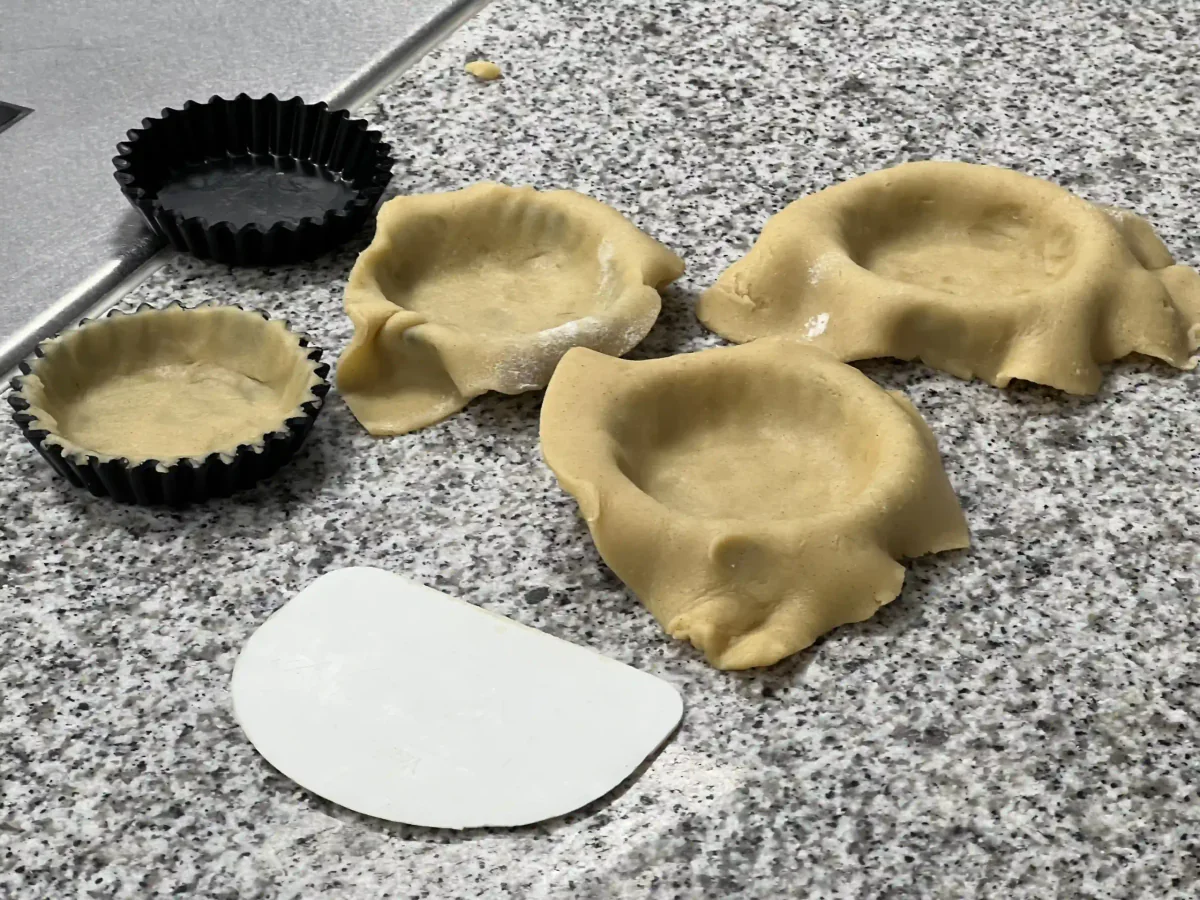 Kleine Tarteformen mit Teig auslegen.