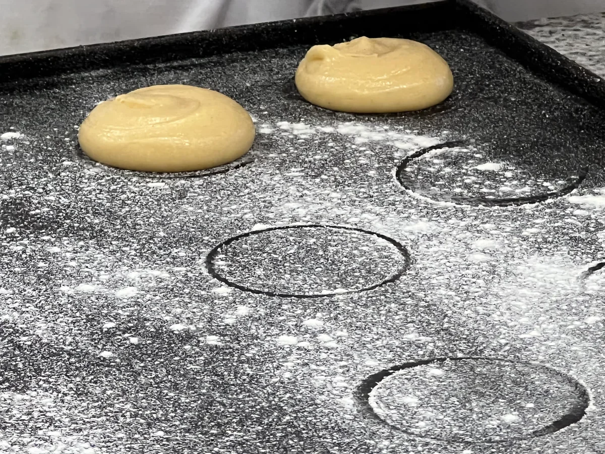 Round portions of choux pastry on a baking tray.