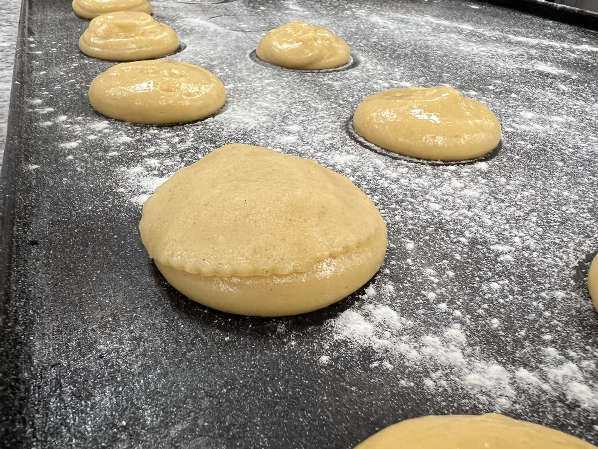 Placing a round dough disc on a portion of choux pastry.