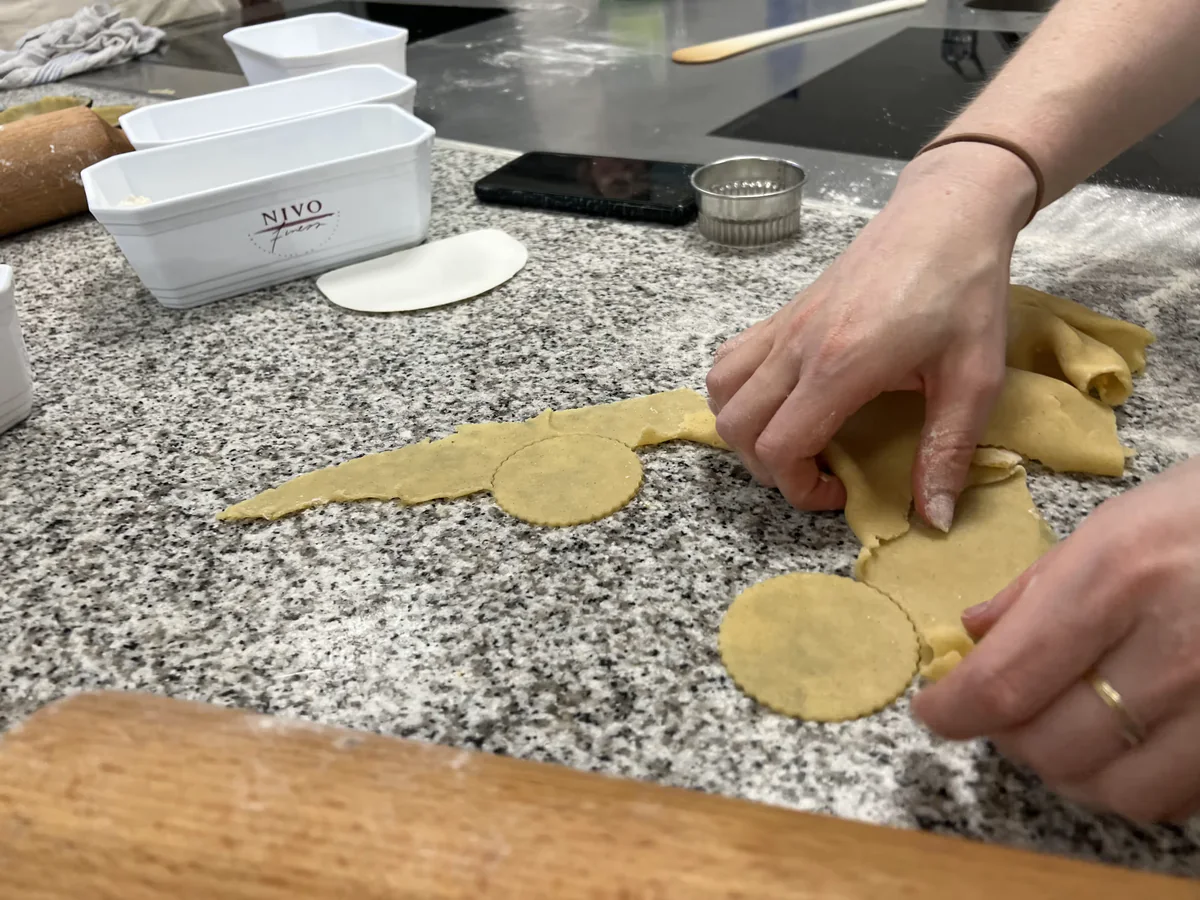 Cutting circles out of thinly rolled pastry.