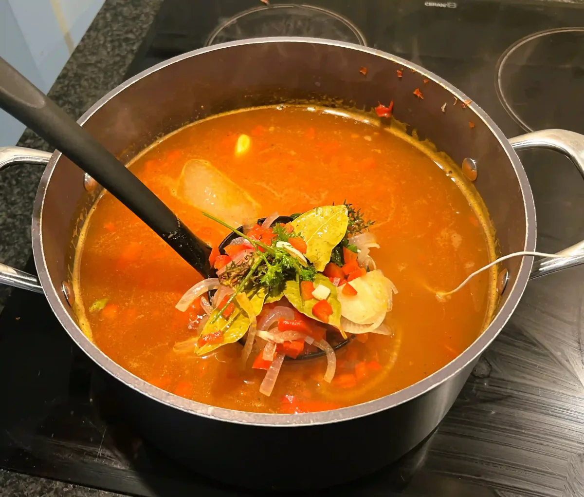Gemüse in Tomatensuppe mit einem Stabmixer im Topf.
