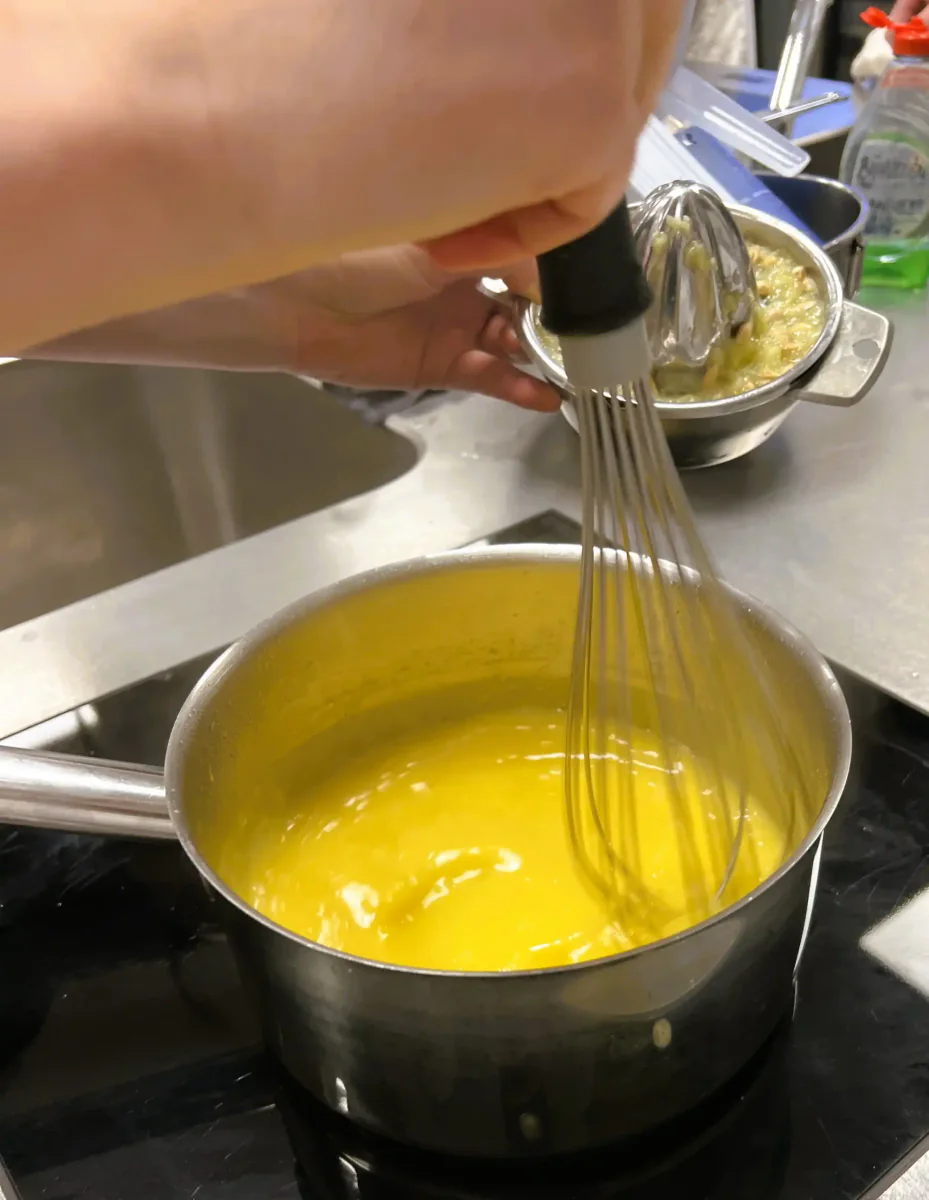 Stirring yellow lemon cream with a whisk.
