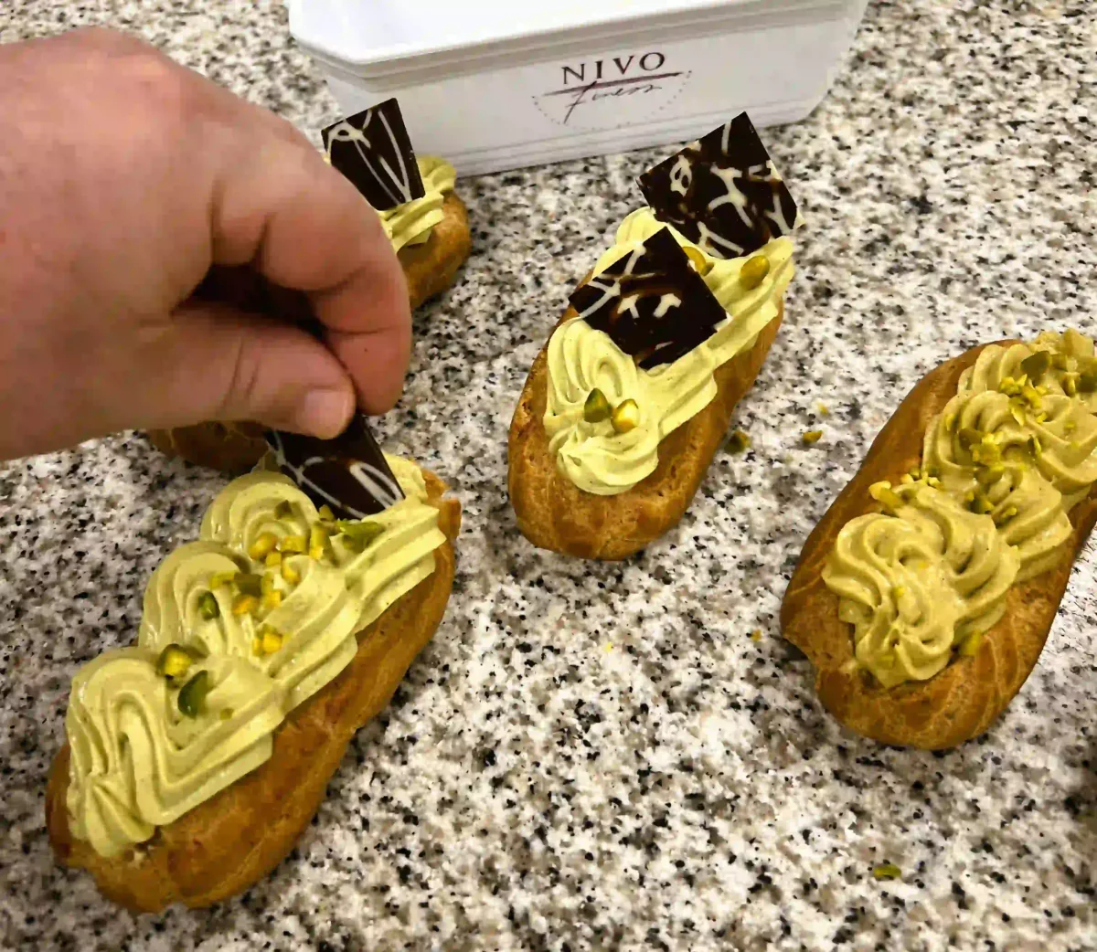 Gevulde eclairs met crème en chocoladedecoratie afwerken.