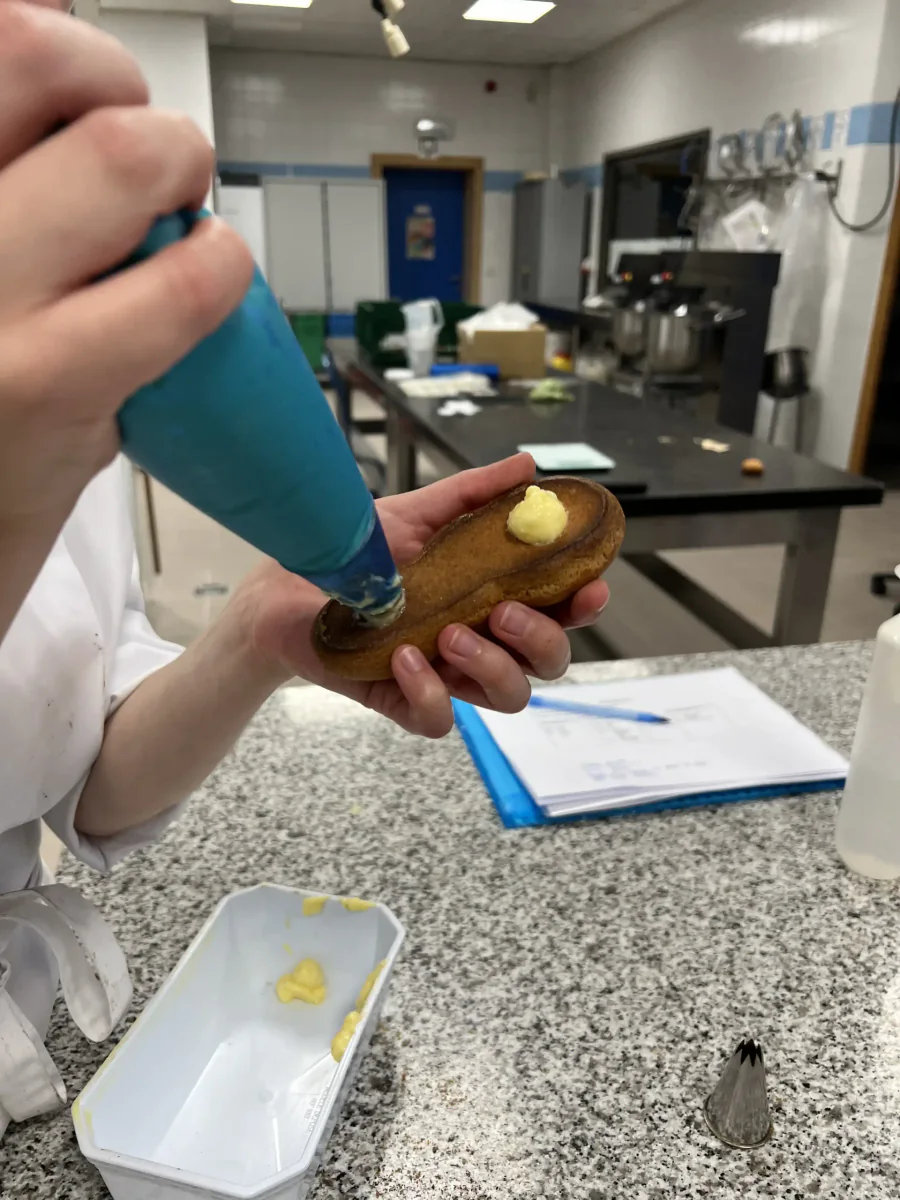 Ein Éclair mit einem Spritzbeutel füllen.