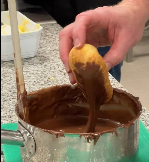 Ein Éclair in Schokoladenglasur tauchen.