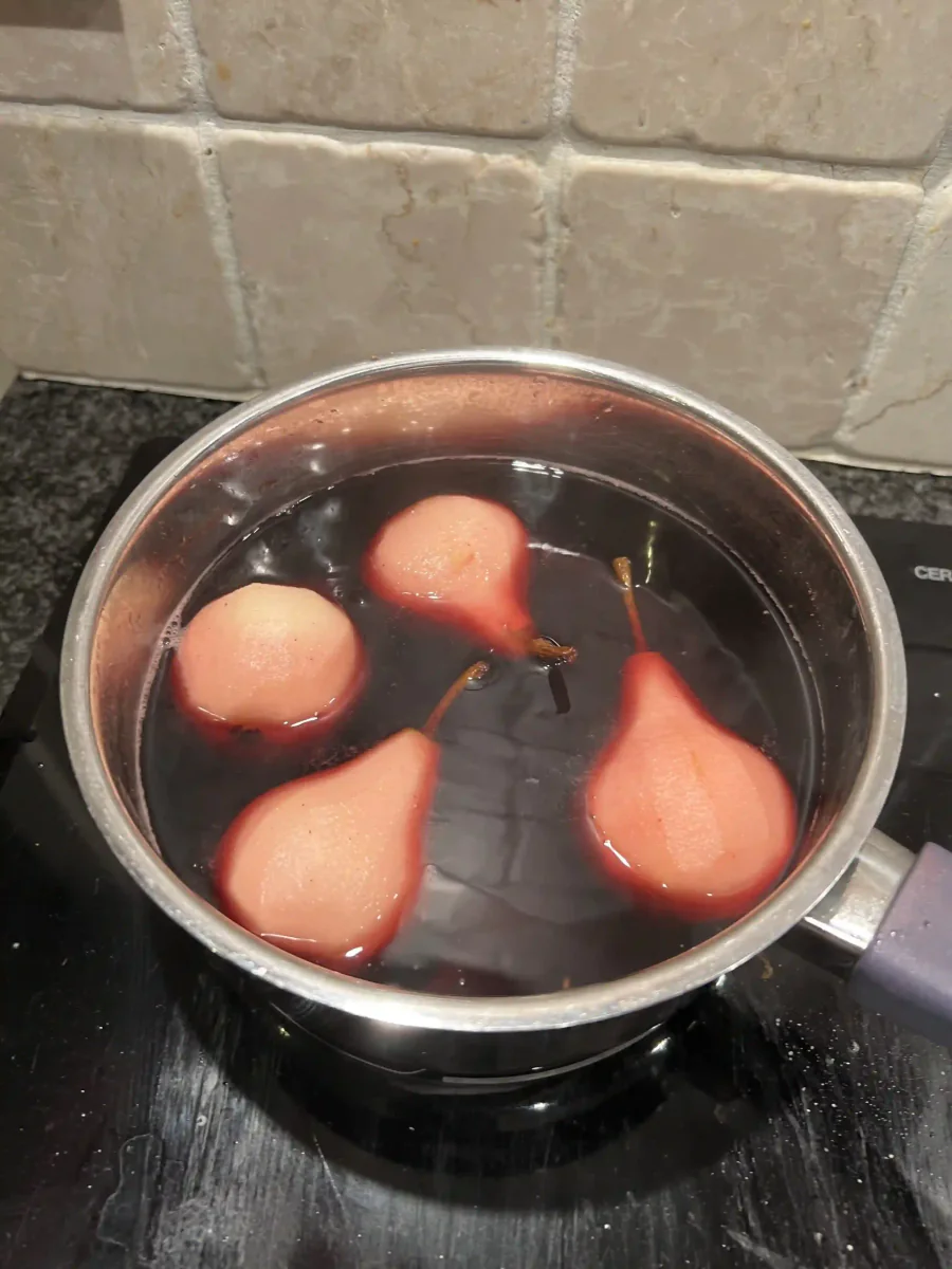 Peeled pears in red wine in a saucepan.