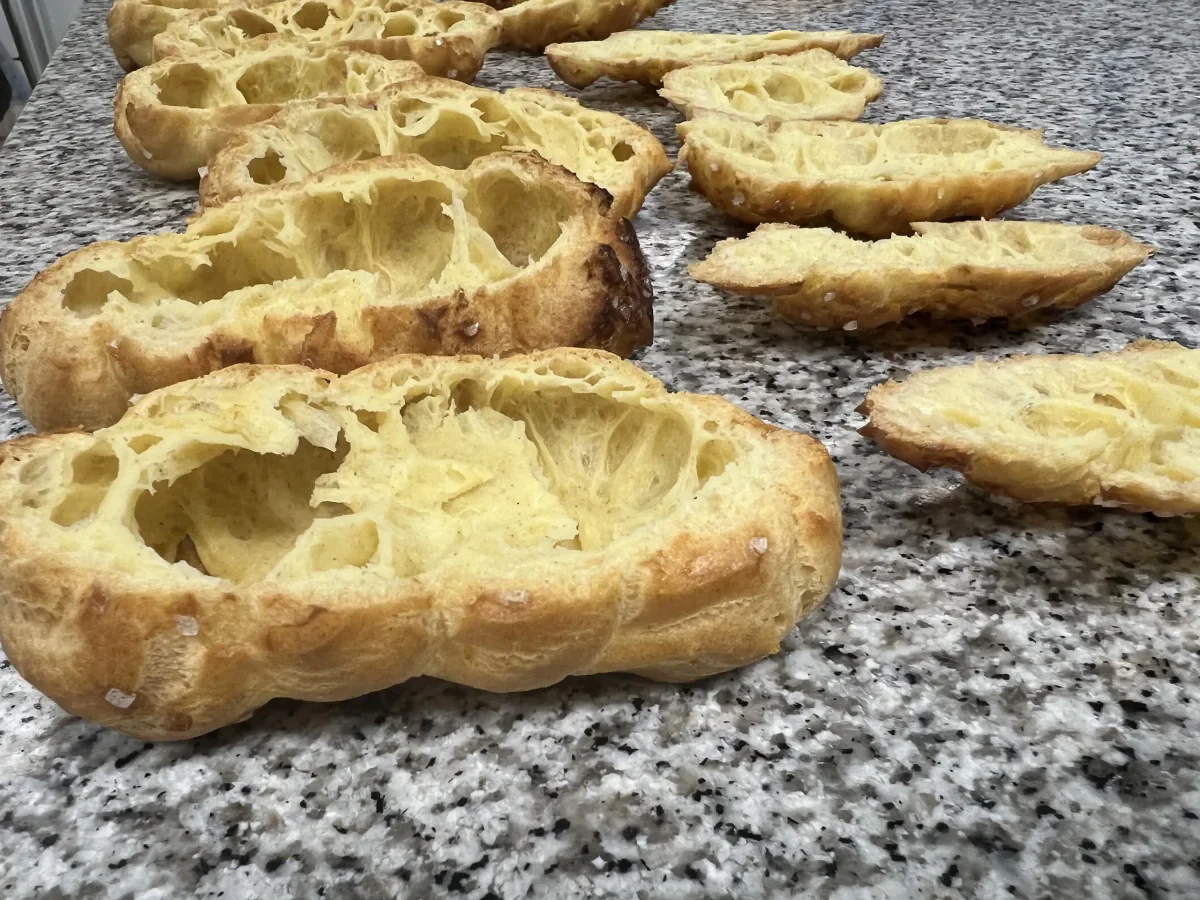 Baked choux pastries cut open horizontally.