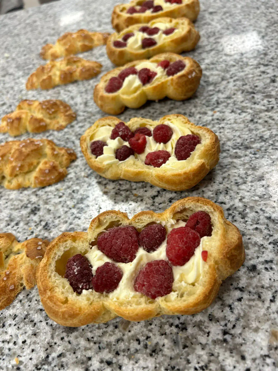 Filling cut-open choux buns with cream and red fruit.
