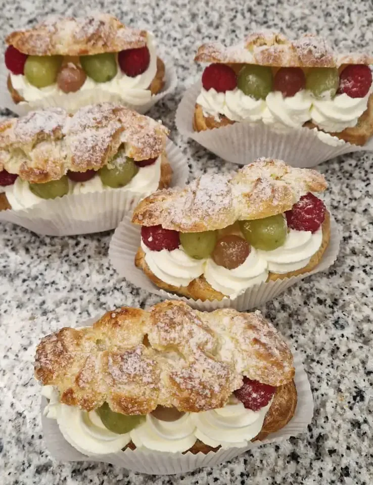 Choux buns finished with whipped cream, fruit and icing sugar.