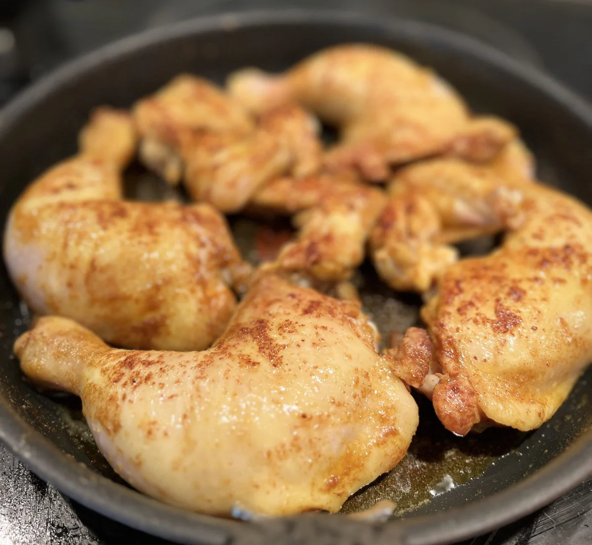 Frying seasoned chicken pieces in a pan.
