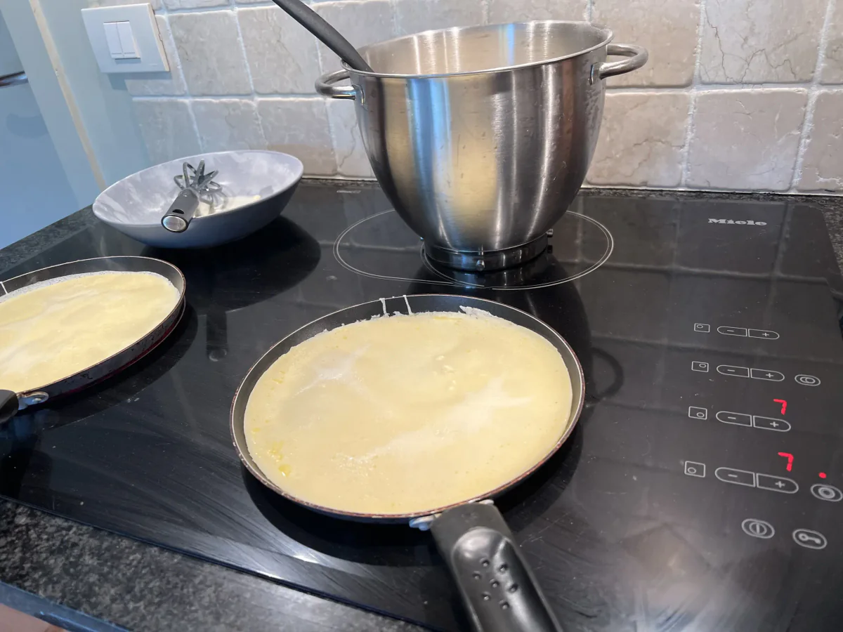 Dos sartenes con masa de tortitas en la placa de cocina.