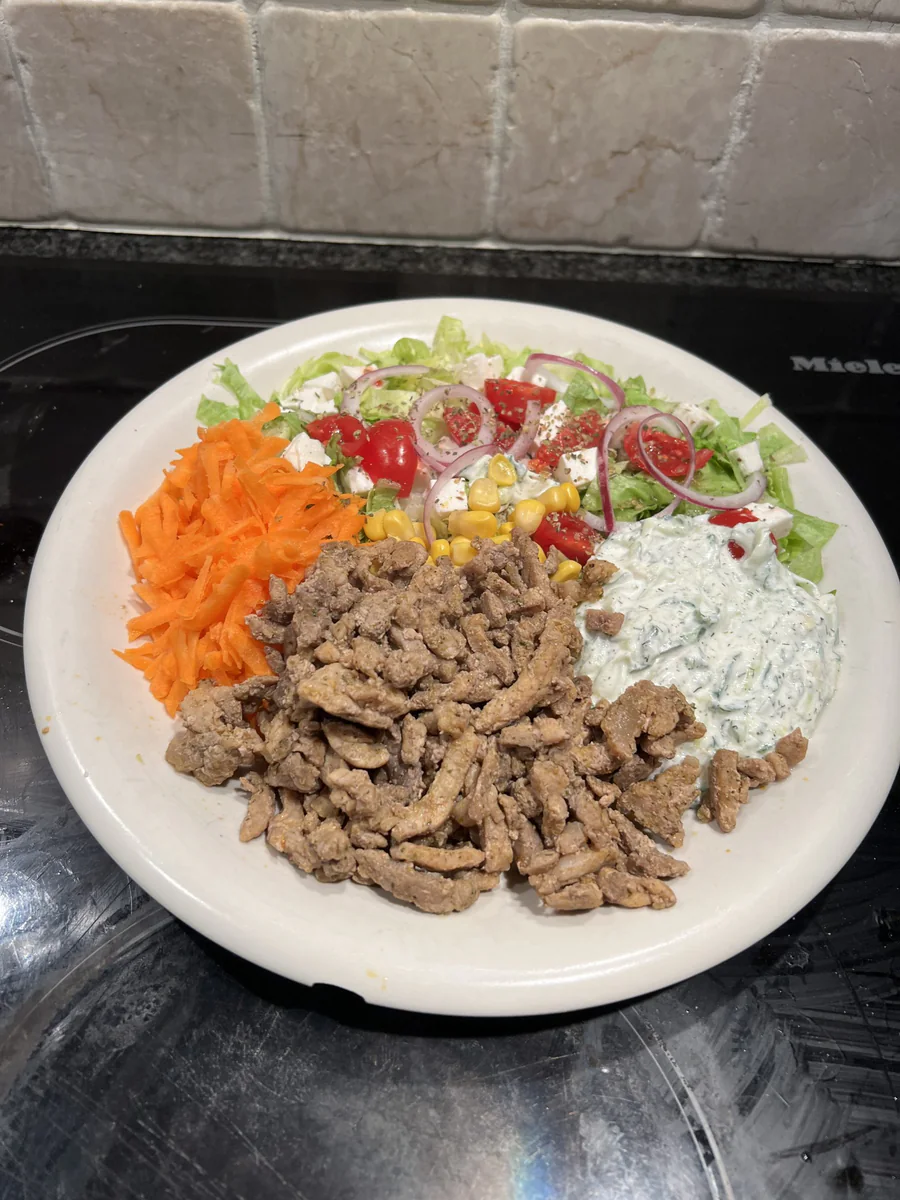 Pitateller Huys mit Fleisch, Tzatziki, Mais, Möhre, Eisbergsalat, Kirschtomaten, roter Zwiebel, Feta, Oregano, Pfeffer und Salz