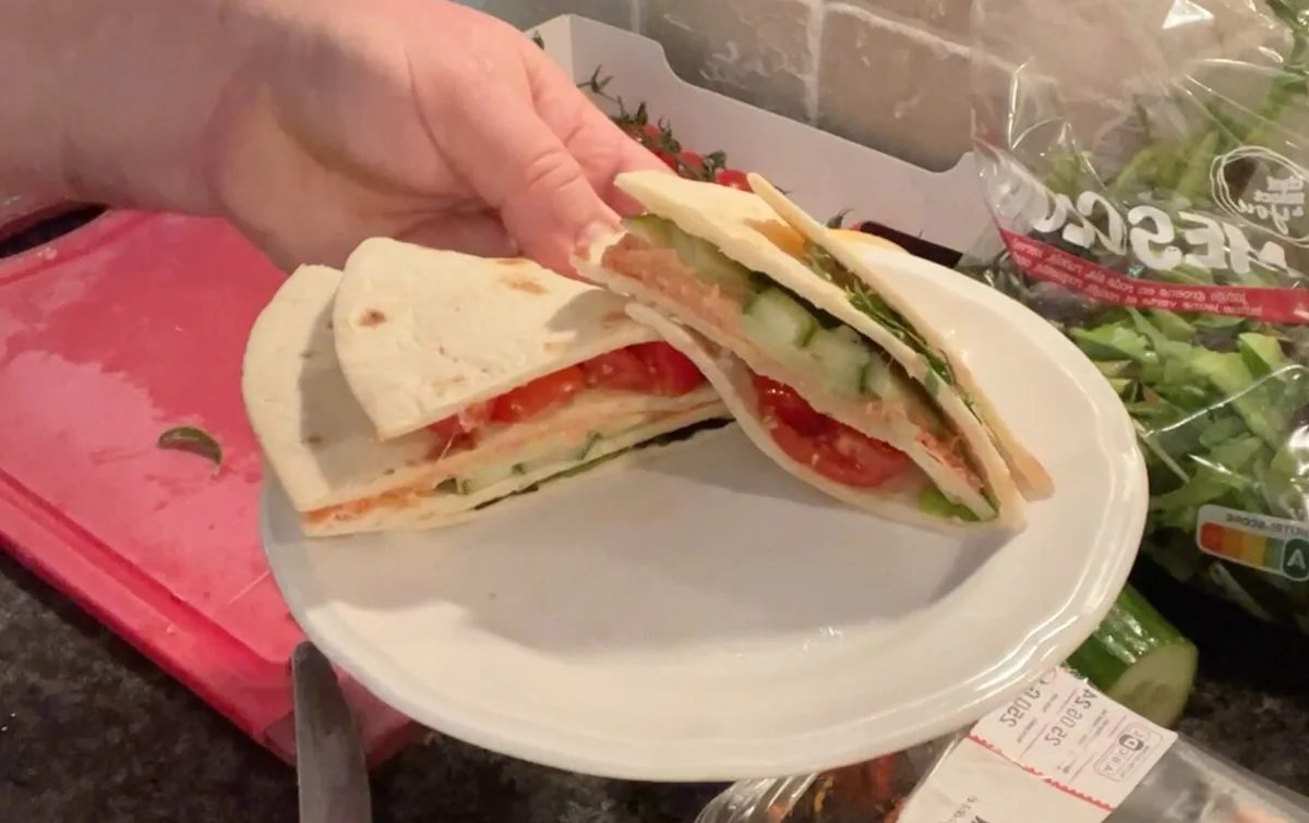 Gefalteter Wrap mit gewürztem Fleischaufstrich, Gurke, Kirschtomaten und Salat