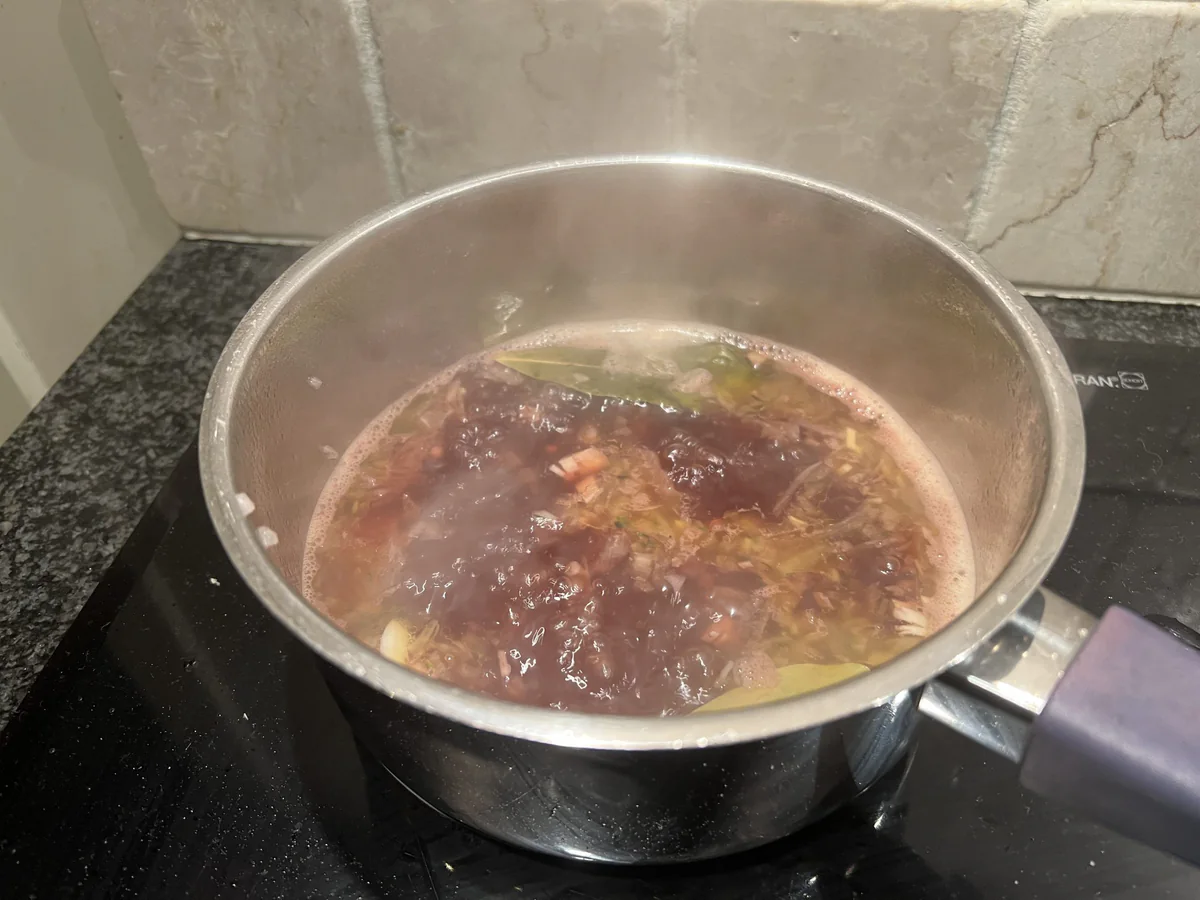 Reducing a dark sauce in a saucepan.