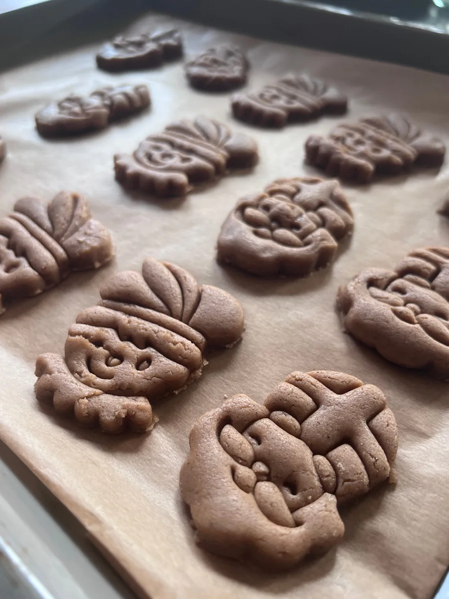 Unbaked shaped biscuits on baking paper.