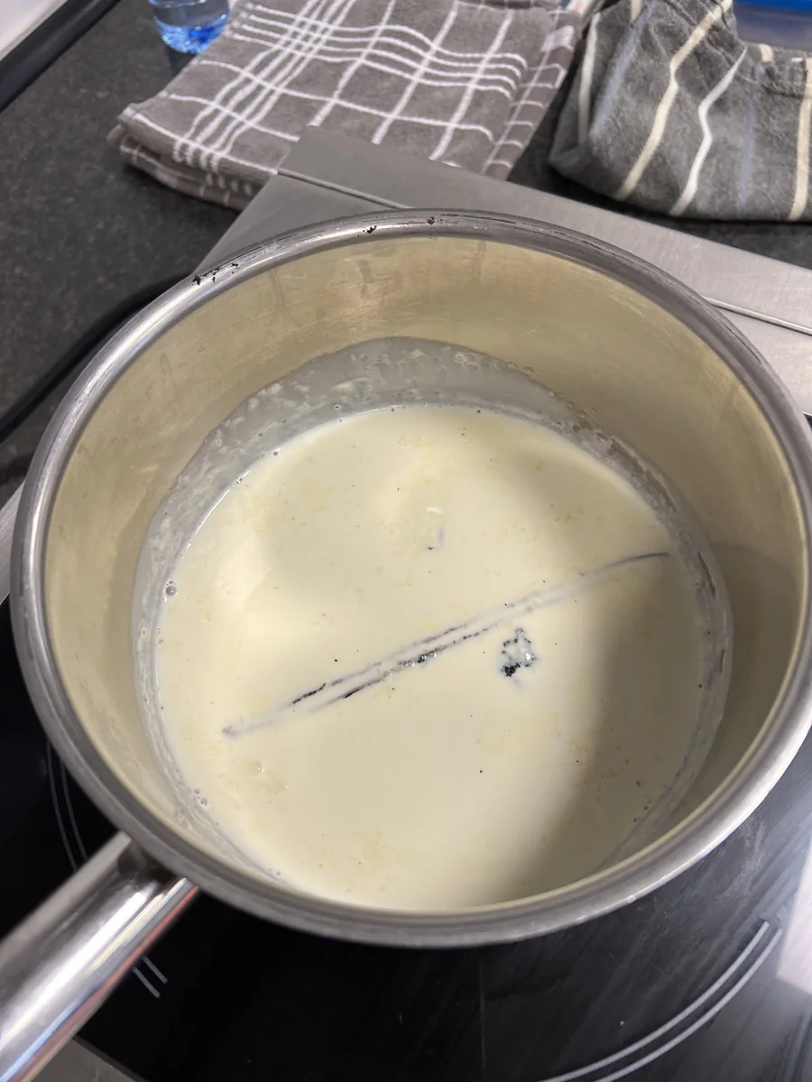 Heating cream with a vanilla pod in a saucepan.