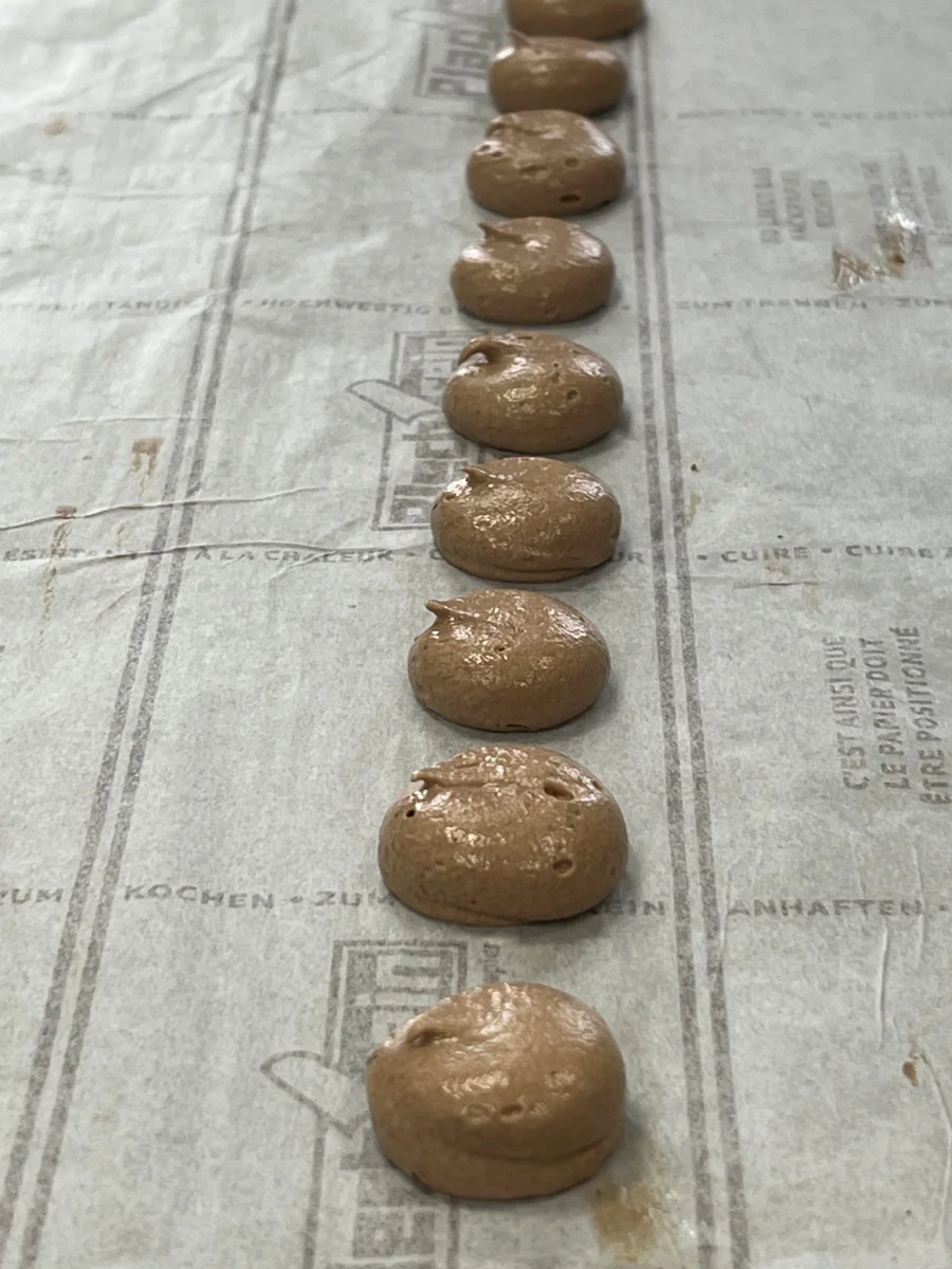Piped portions of chocolate filling on a work surface.