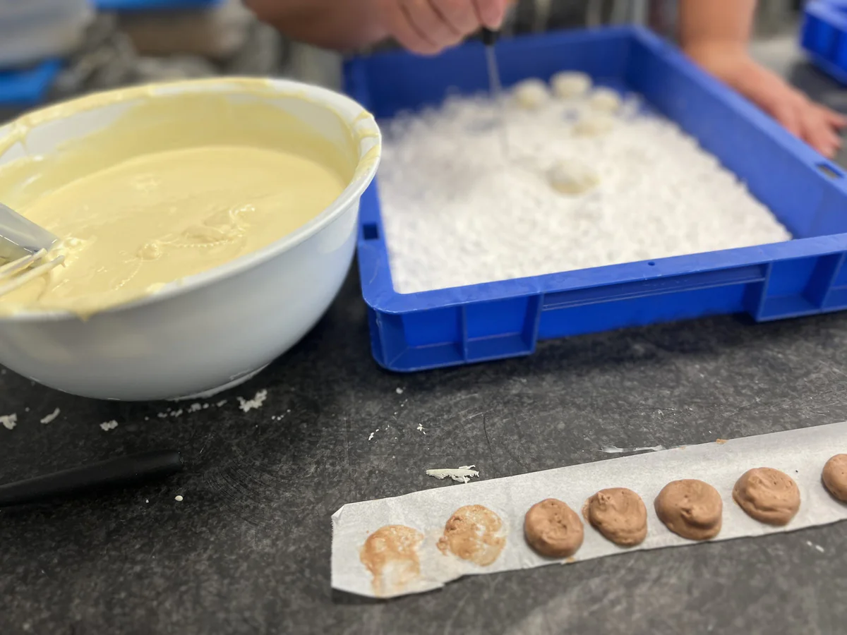 A bowl of white chocolate beside coconut and portions of filling.