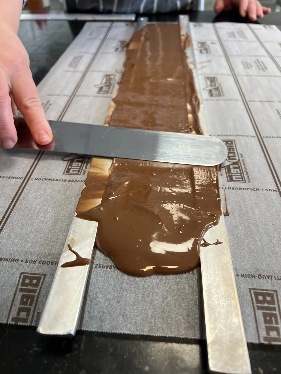 Spreading a layer of chocolate between straight spacer bars.