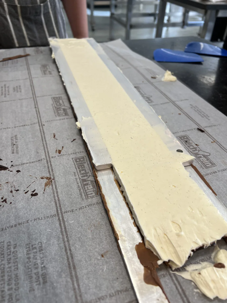Spreading pale cream over a rectangular layer.