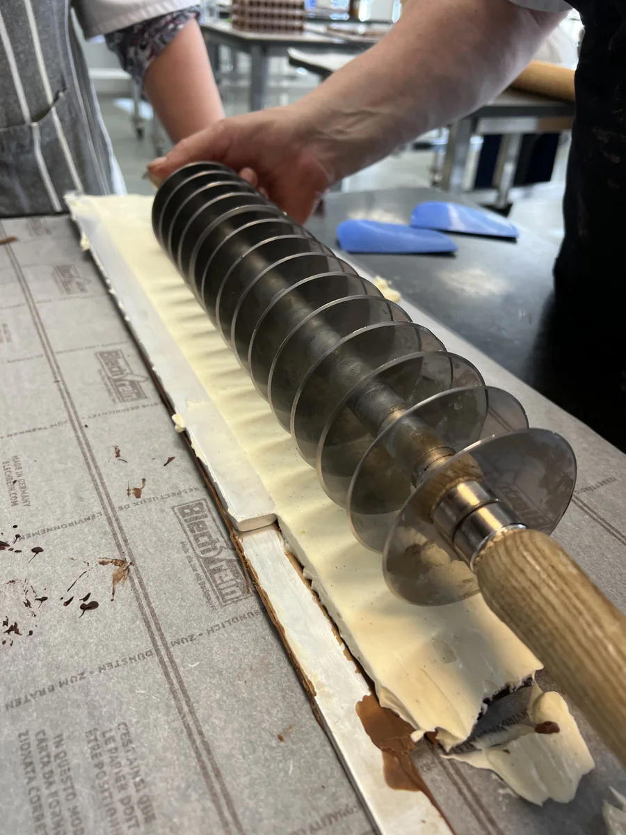 Dividing a rectangular pastry with a multi-wheel pastry cutter.