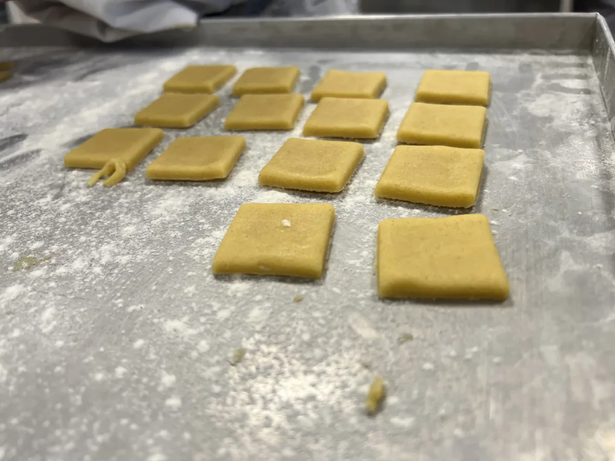 Square pieces of pastry on a baking tray.
