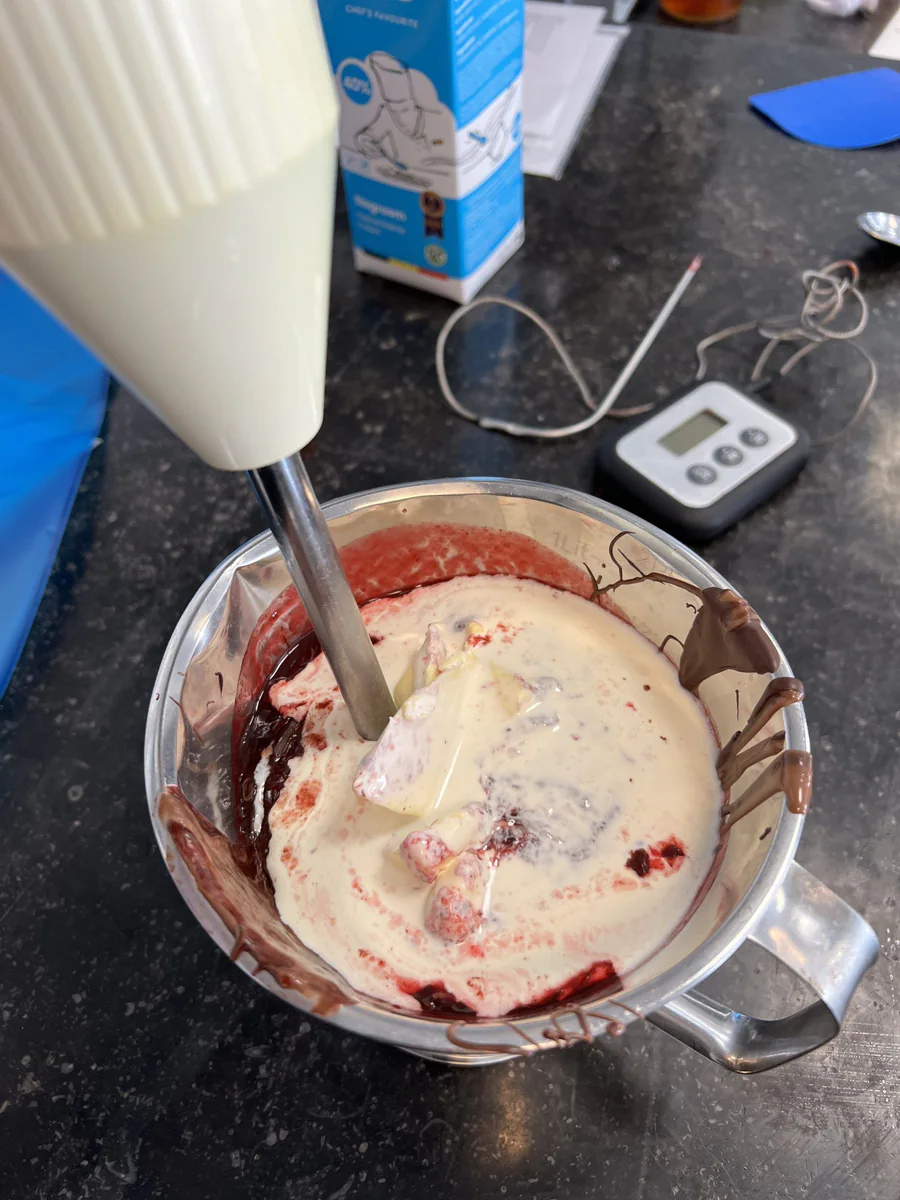 Folding a red fruit mixture into a pale cream.