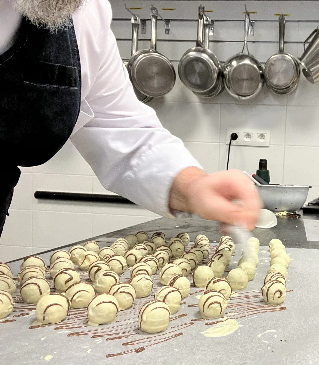 Schokoladenkugeln mit dünnen Schokoladenstreifen verzieren.