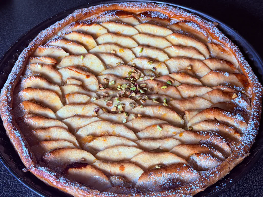 Appeltaart met frangipane, glanzende appelschijfjes, pistachenootjes en bloemsuiker