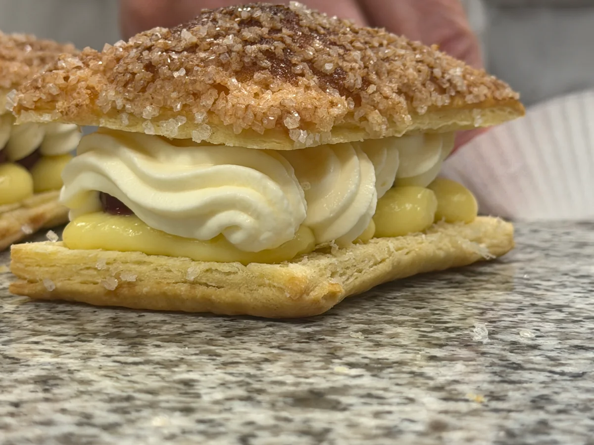 Eine fertige Allumette mit gezuckerter Haube und Sahne über den Sauerkirschen.