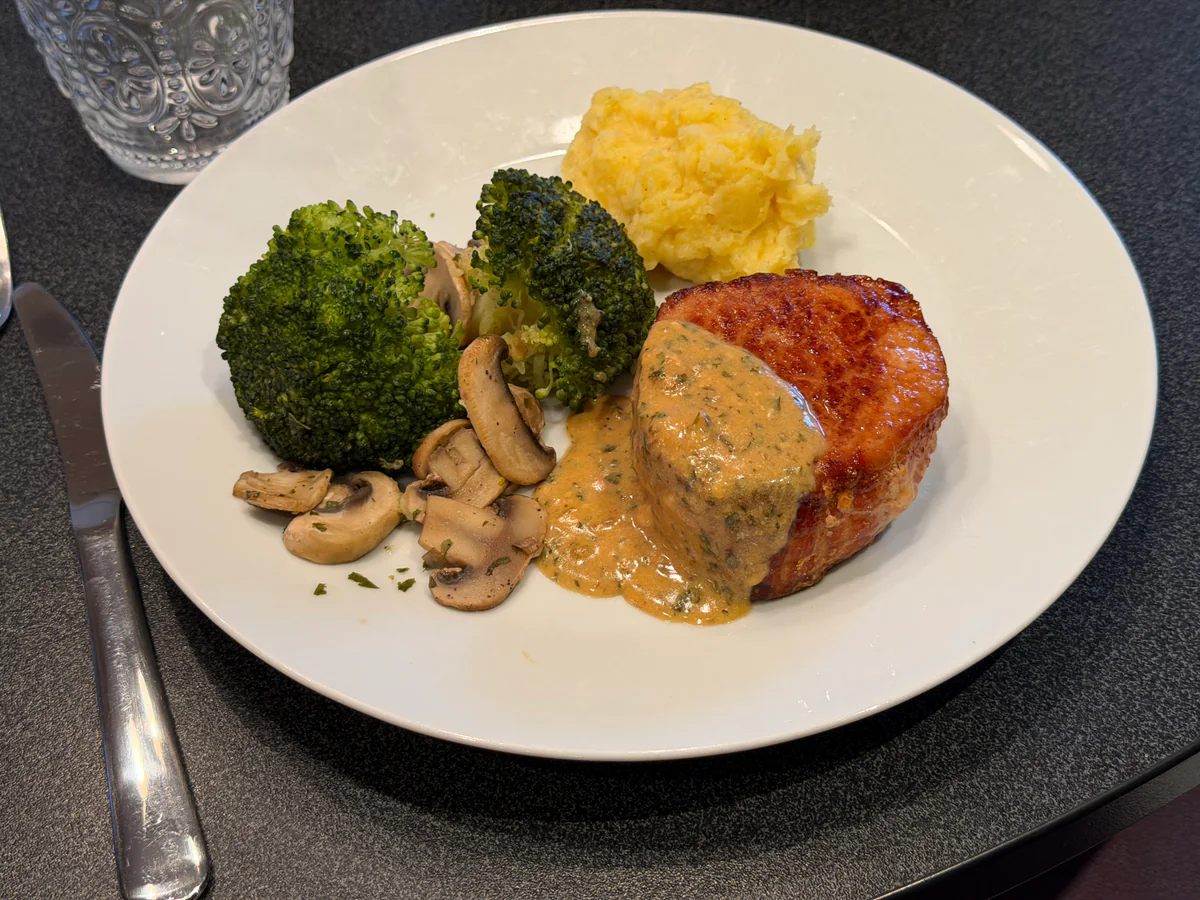 Geserveerde varkensoester met saus, puree, broccoli en champignons