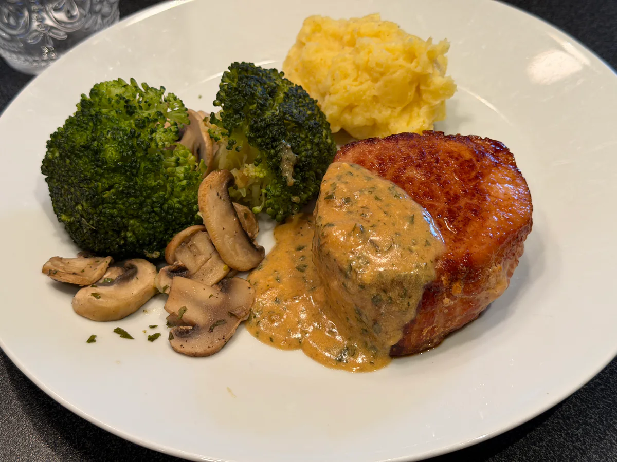 Varkensoester op Ardense wijze met mosterd-roomsaus, puree, broccoli en champignons op een wit bord