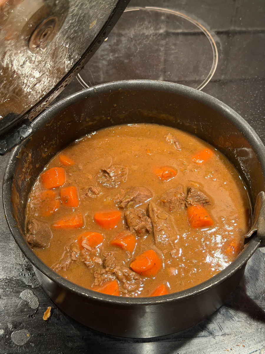 Hertenragout met stukken wortel in bruine saus in de stoofpot.
