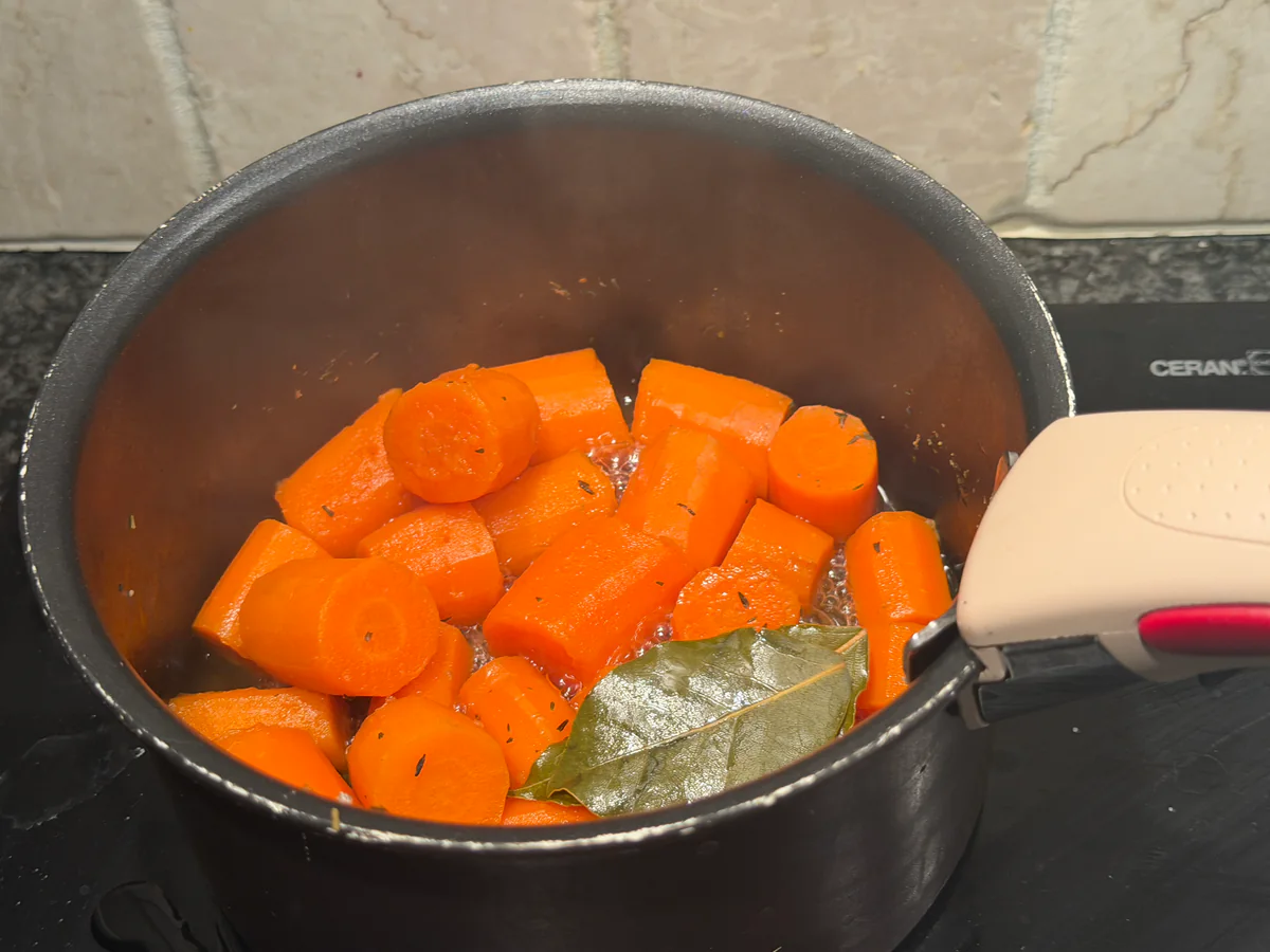 Grove stukken wortel met laurier en tijm in de kookpot