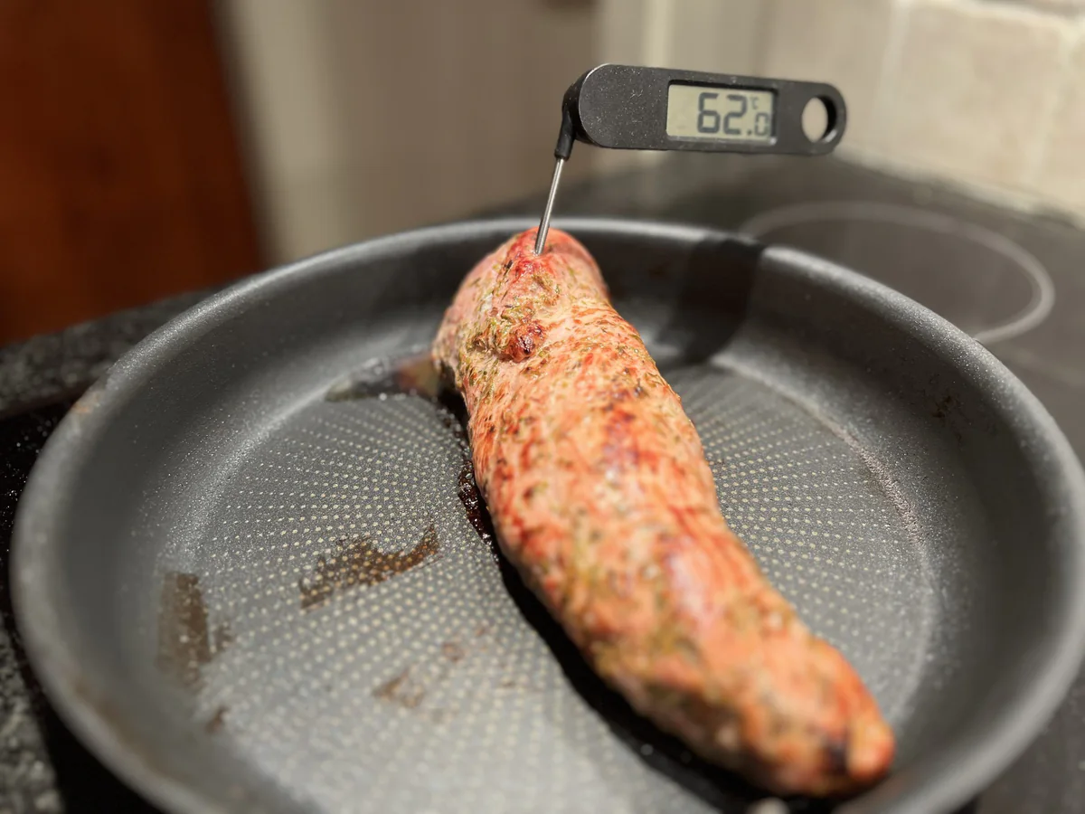 Fleisch in einer Pfanne mit einem Kerntemperaturfühler.