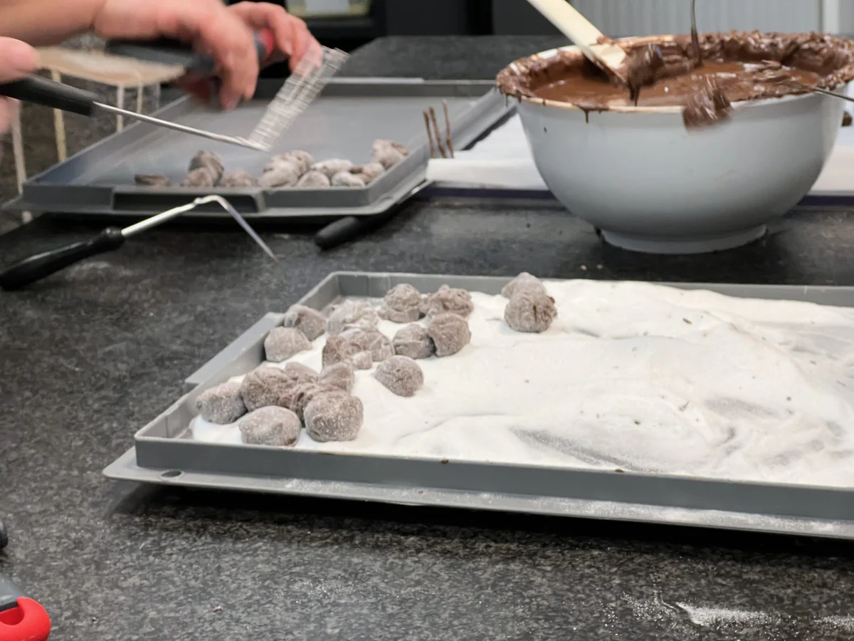 Rolling chocolate truffles in icing sugar.