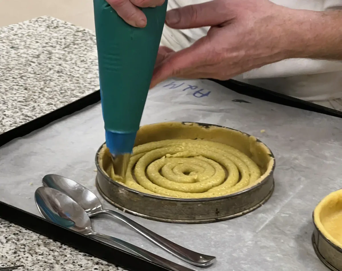 Piping filling in a spiral onto a tart base.