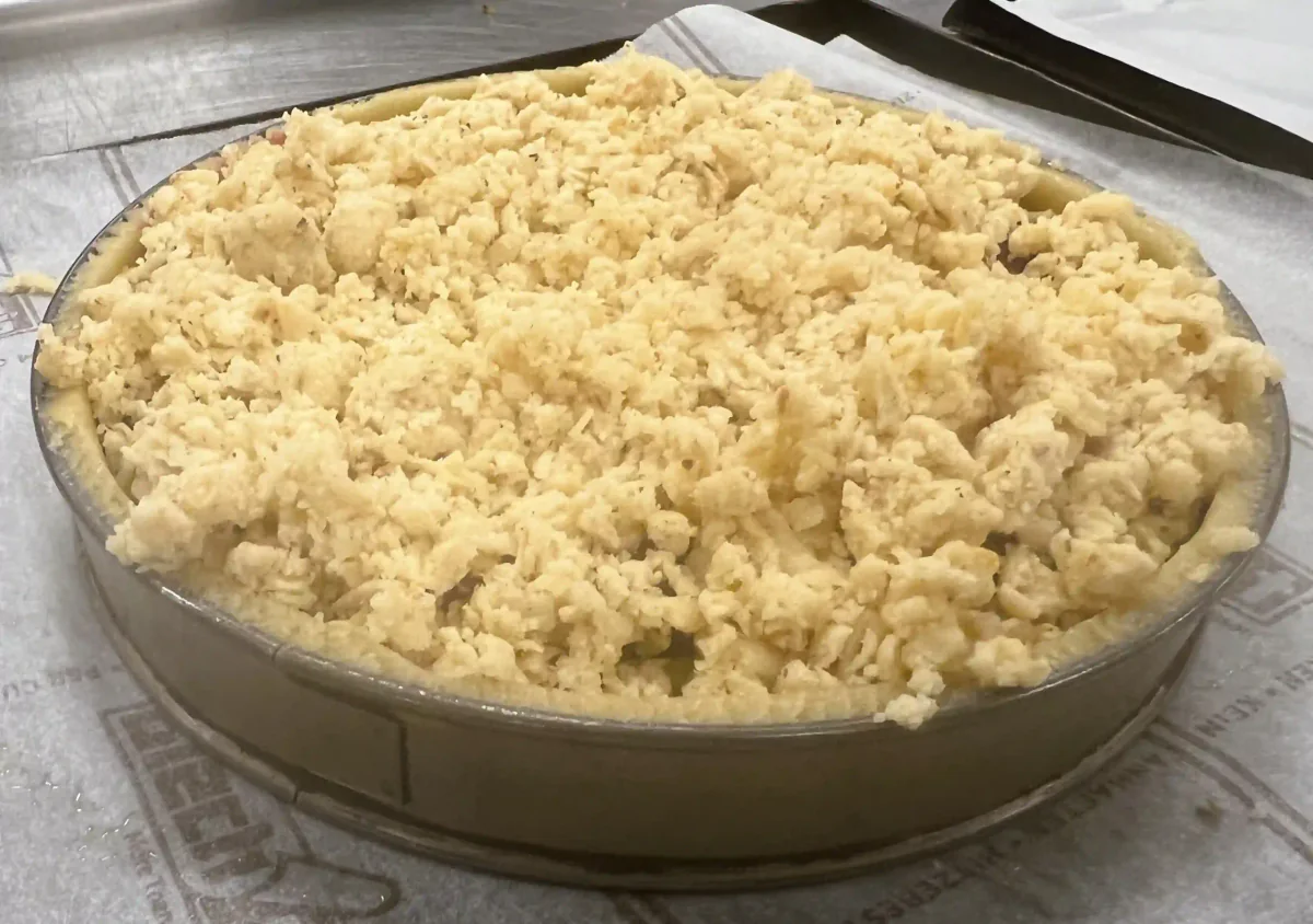 An unbaked tart covered with pastry crumbs.