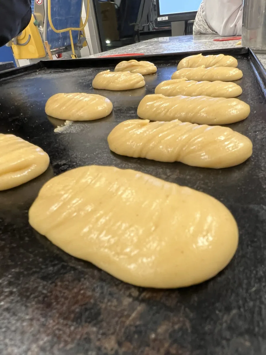 Tropfenförmige Brandteigportionen auf einem Backblech.