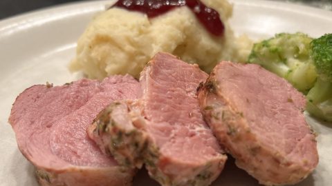 Varkenshaasje versneden op het bord met een portie broccoli en puree met rode bessen saus
