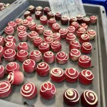 Truffel framboos afgewerkt met een rode verflaag en een spiraal van witte chocolade