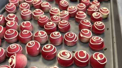 Truffel framboos afgewerkt met een rode verflaag en een spiraal van witte chocolade