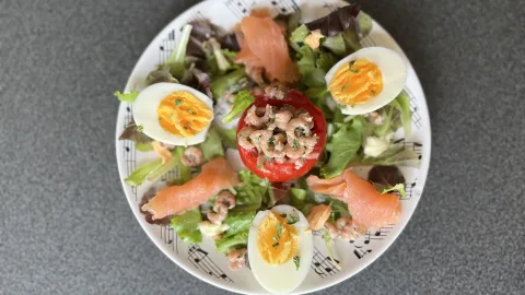 Tomaat garnaal op een bedje van sla afgwerkt met zalm en ei