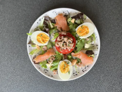 Tomaat garnaal op een bedje van sla afgwerkt met zalm en ei