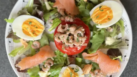 Tomaat garnaal op een bedje van sla afgwerkt met zalm en ei