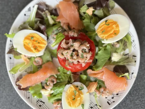 Tomaat garnaal op een bedje van sla afgwerkt met zalm en ei